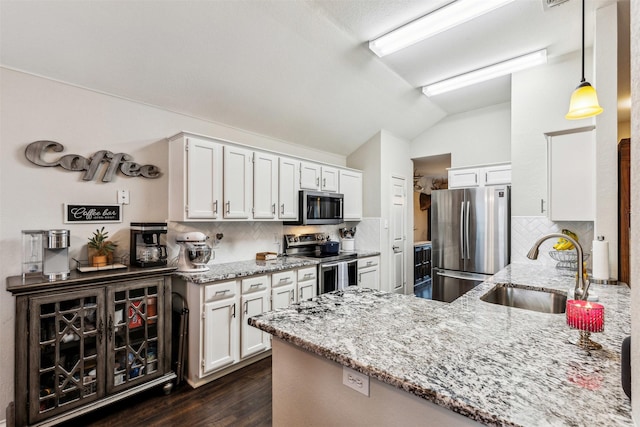 kitchen featuring vaulted ceiling, appliances with stainless steel finishes, decorative light fixtures, sink, and white cabinets