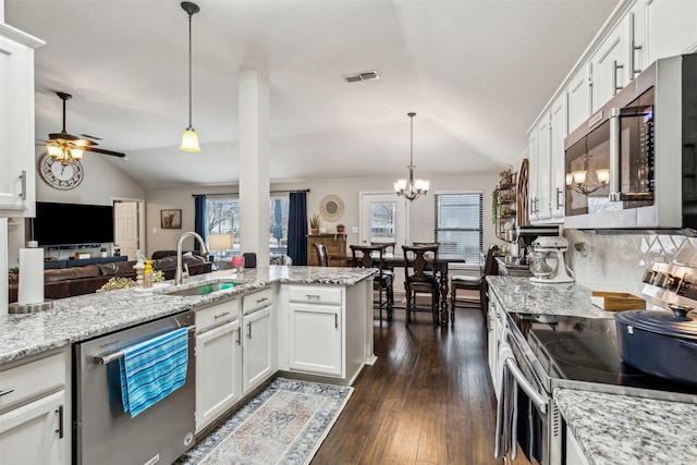 kitchen featuring white cabinetry, appliances with stainless steel finishes, decorative light fixtures, and vaulted ceiling