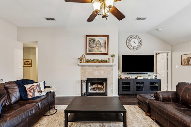 living room with ceiling fan, lofted ceiling, wood-type flooring, and a tiled fireplace