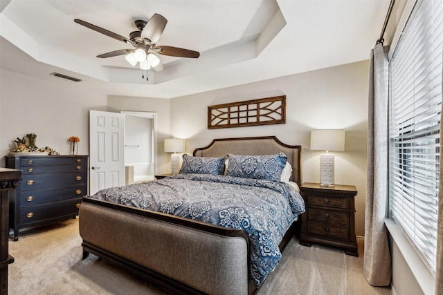 bedroom with a raised ceiling, light colored carpet, and ceiling fan