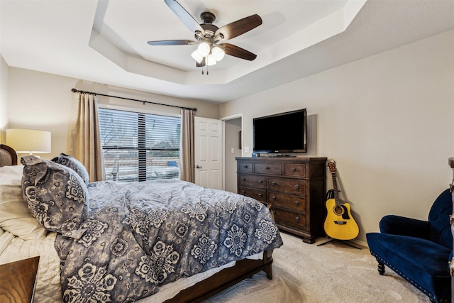 carpeted bedroom featuring a tray ceiling and ceiling fan