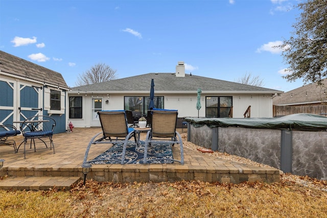 back of house with a patio area, a covered pool, and a storage unit