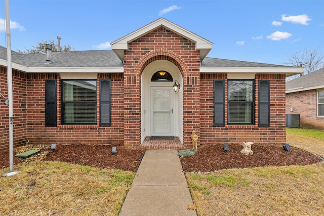 view of exterior entry with central AC and a lawn