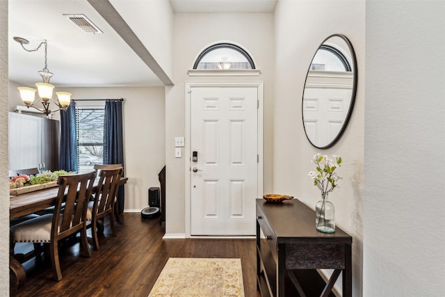 entryway with an inviting chandelier and dark hardwood / wood-style flooring