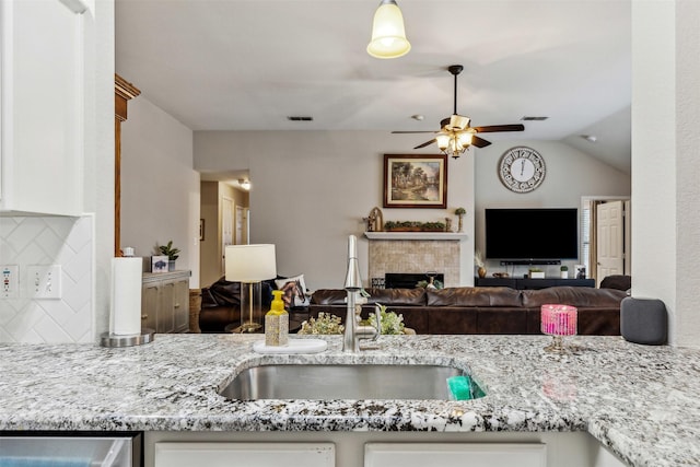 kitchen featuring light stone counters, white cabinets, sink, and backsplash