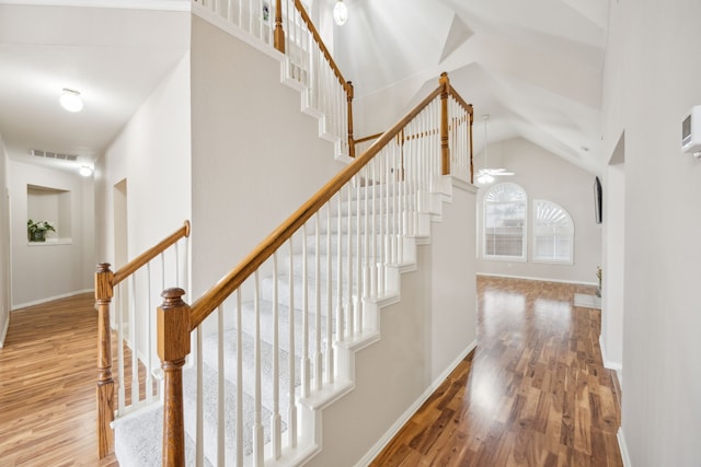 stairs with high vaulted ceiling and hardwood / wood-style floors