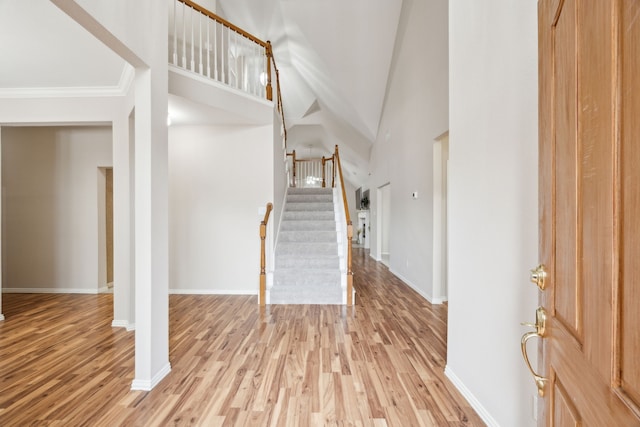 entryway with a high ceiling, crown molding, and light hardwood / wood-style floors