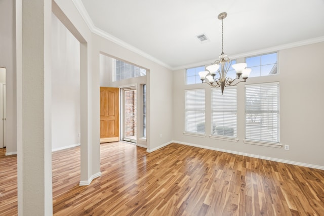 unfurnished dining area with hardwood / wood-style floors, crown molding, and a notable chandelier