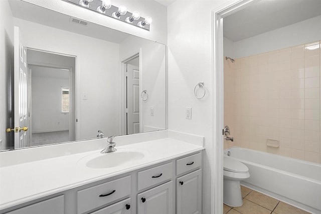 full bathroom featuring vanity, tiled shower / bath, tile patterned floors, and toilet