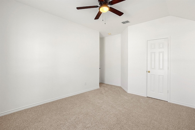 spare room featuring ceiling fan, light colored carpet, and lofted ceiling