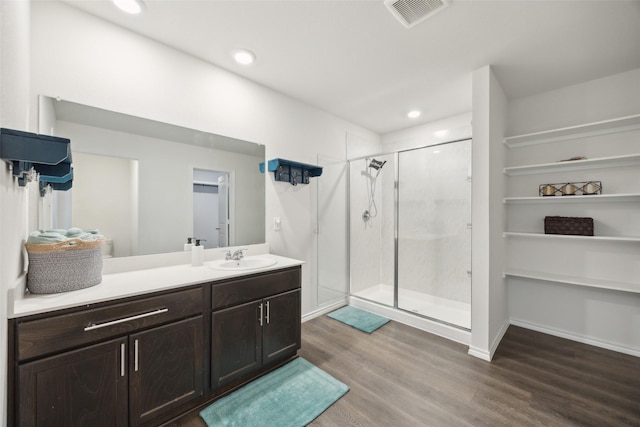 bathroom featuring hardwood / wood-style flooring, vanity, and walk in shower