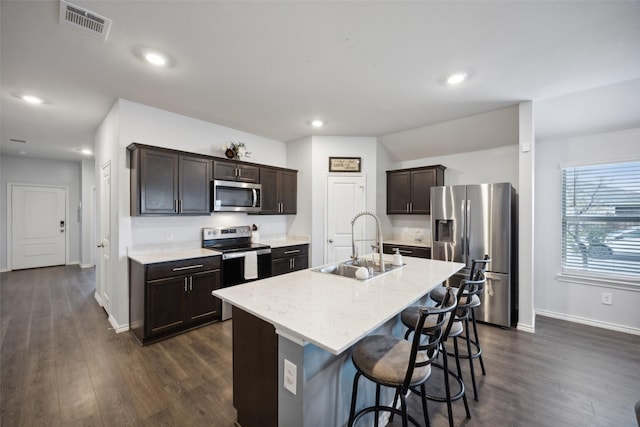 kitchen featuring stainless steel appliances, sink, a center island with sink, and dark wood-type flooring