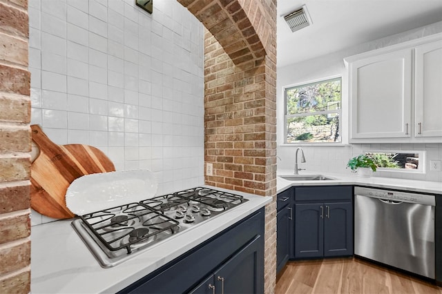 kitchen featuring dishwasher, sink, white cabinets, backsplash, and gas cooktop