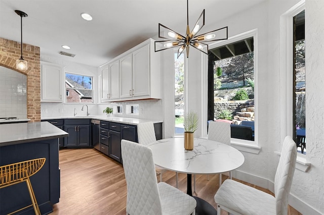 kitchen with pendant lighting, sink, white cabinetry, and decorative backsplash