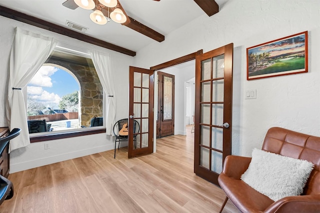 sitting room with french doors, ceiling fan, light hardwood / wood-style floors, and beamed ceiling