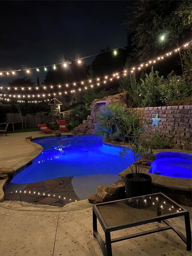 view of pool featuring a patio area, pool water feature, and an in ground hot tub