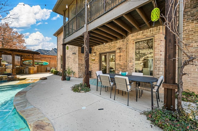 view of patio / terrace with a balcony, an outdoor kitchen, and a swimming pool