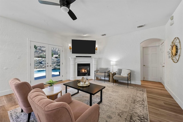 living room featuring french doors, ceiling fan, and light hardwood / wood-style flooring