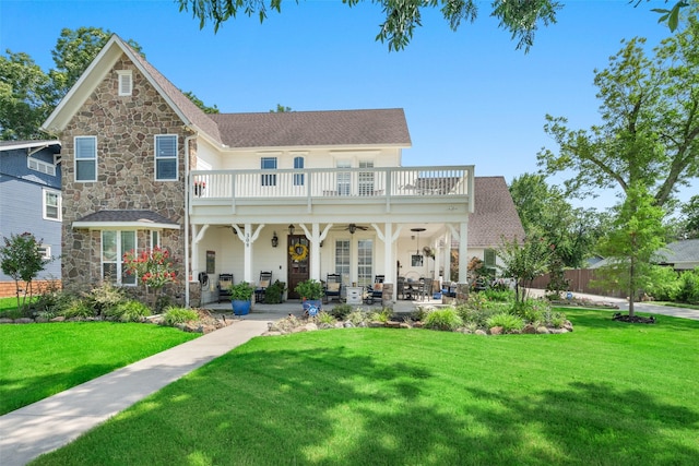 rear view of house with ceiling fan, a yard, a balcony, and a patio