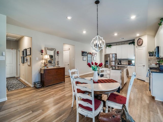 dining area with an inviting chandelier, sink, and light hardwood / wood-style flooring