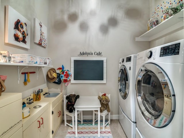 washroom featuring sink, washing machine and dryer, cabinets, and light tile patterned flooring