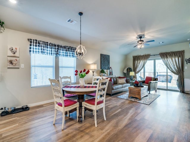 dining space with hardwood / wood-style flooring and ceiling fan with notable chandelier