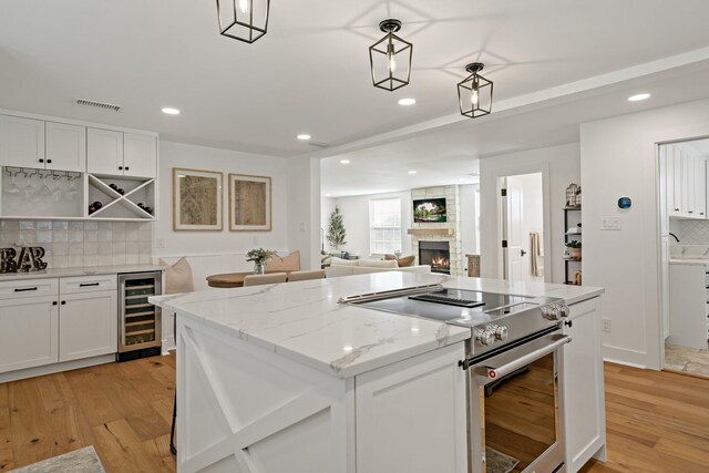 209 Mary Fitch Rd, Sherman, TX 75090 - kitchen with beverage cooler, high end stove, a center island, decorative backsplash, and a stone fireplace