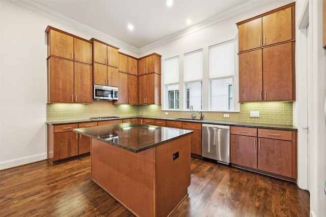 kitchen featuring dark hardwood / wood-style flooring, ornamental molding, a center island, and appliances with stainless steel finishes