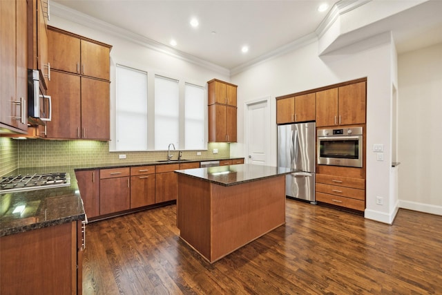 kitchen with sink, appliances with stainless steel finishes, a center island, ornamental molding, and dark hardwood / wood-style flooring