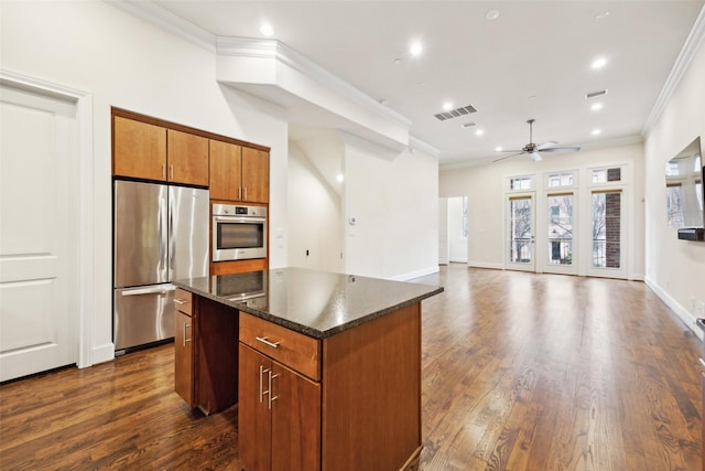 kitchen featuring dark hardwood / wood-style flooring, ornamental molding, stainless steel appliances, and a kitchen island