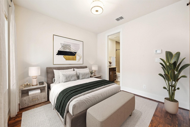 bedroom with connected bathroom and dark wood-type flooring