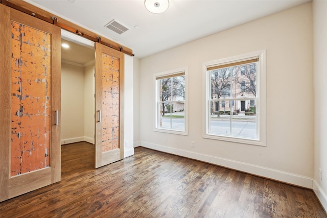 unfurnished bedroom featuring dark hardwood / wood-style floors and a barn door