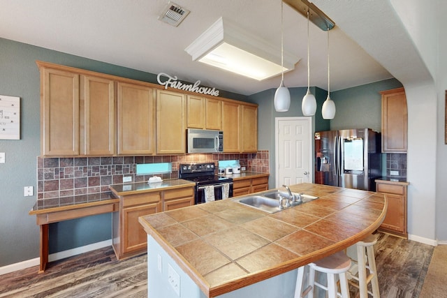 kitchen featuring appliances with stainless steel finishes, tile counters, sink, and a center island with sink