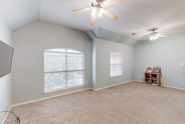 spare room with vaulted ceiling, a wealth of natural light, light colored carpet, and ceiling fan