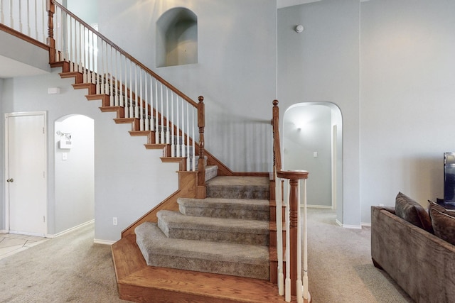 stairway featuring a high ceiling and carpet