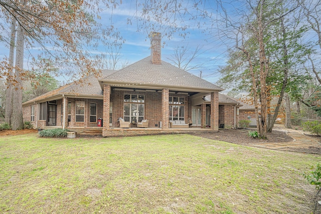 rear view of house featuring a yard and a sunroom