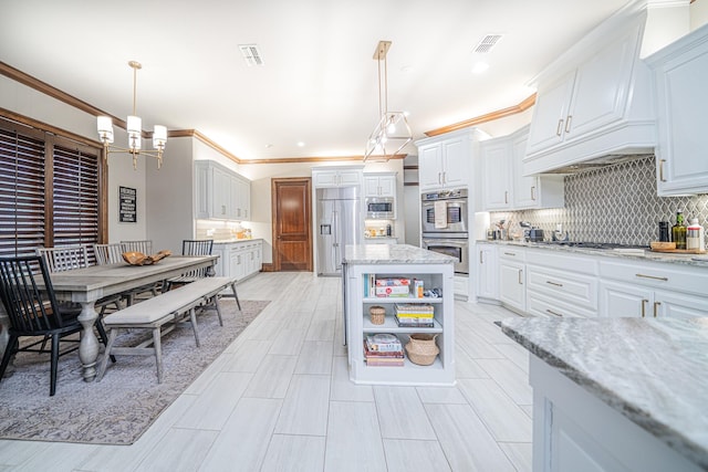 kitchen featuring built in appliances, light stone counters, decorative light fixtures, and white cabinets