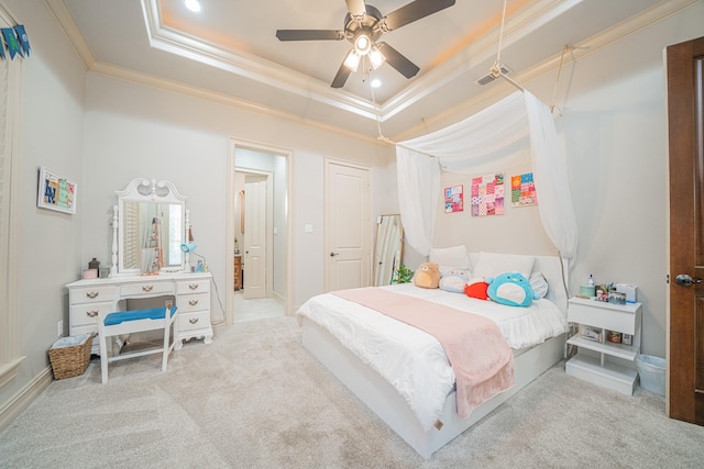 carpeted bedroom featuring crown molding, ensuite bathroom, ceiling fan, and a tray ceiling