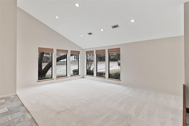 carpeted spare room with high vaulted ceiling