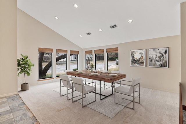 dining area with light colored carpet, a healthy amount of sunlight, and high vaulted ceiling