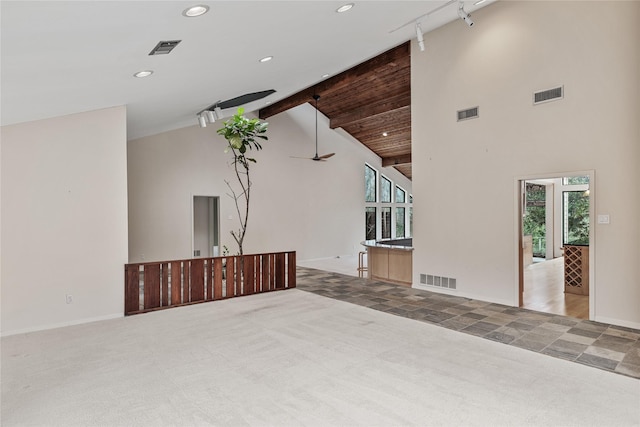 unfurnished living room featuring ceiling fan, beam ceiling, high vaulted ceiling, carpet, and track lighting