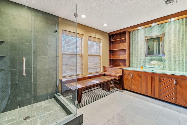 bathroom featuring vanity, an enclosed shower, a textured ceiling, and tile walls