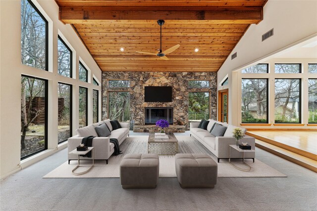 sunroom / solarium featuring vaulted ceiling with beams, a stone fireplace, wooden ceiling, and ceiling fan