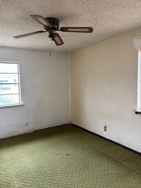 carpeted empty room with ceiling fan and a textured ceiling