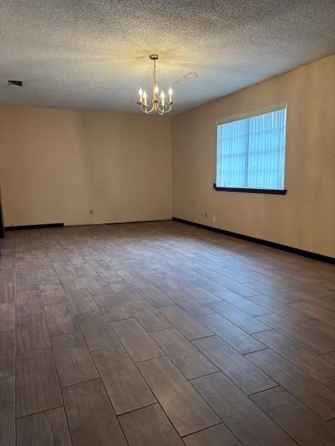 unfurnished room featuring an inviting chandelier, hardwood / wood-style floors, and a textured ceiling