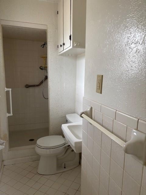 bathroom featuring tile patterned floors, toilet, and tiled shower