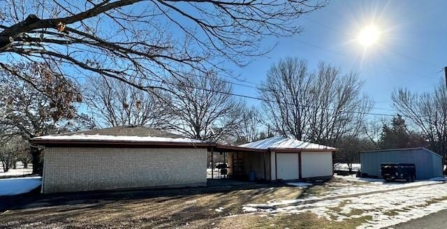 view of snow covered exterior with a garage and an outdoor structure