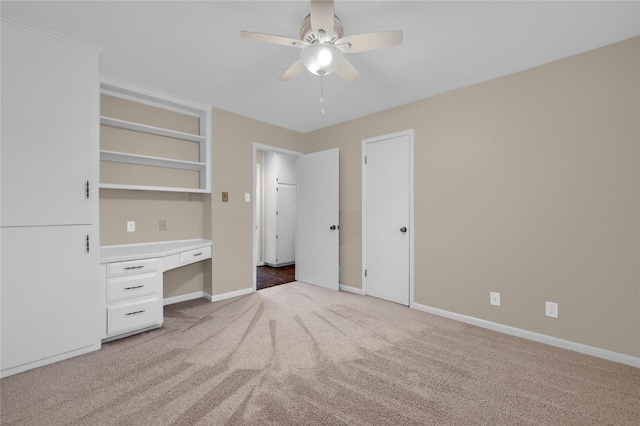 unfurnished bedroom with ceiling fan, built in desk, and carpet floors