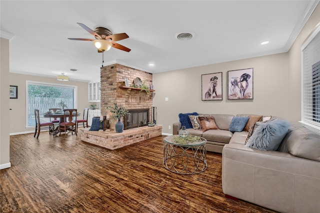 living room featuring crown molding, ceiling fan, hardwood / wood-style floors, and a brick fireplace