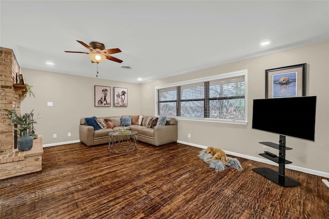 living room featuring a fireplace, dark wood-type flooring, ornamental molding, and ceiling fan